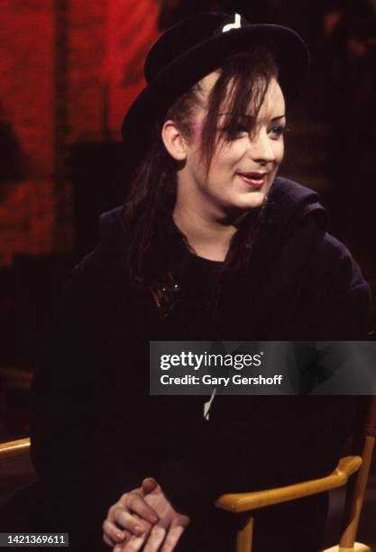 View of British Pop musician Boy George , of the group Culture Club, as he sits in a director's chair during an interview on MTV at Teletronic...