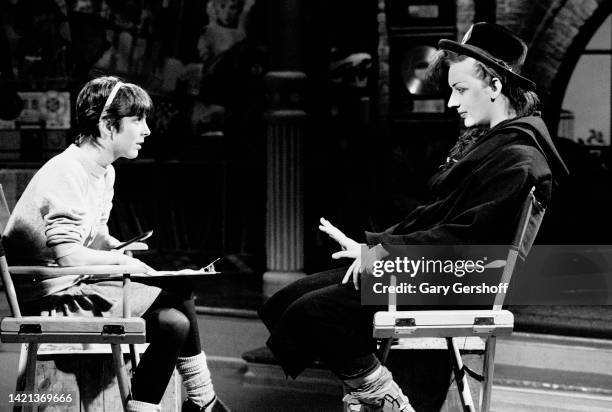 View of MTV VJ Martha Quinn and British Pop musician Boy George , of the group Culture Club, as they sit in a director's chairs during an interview...