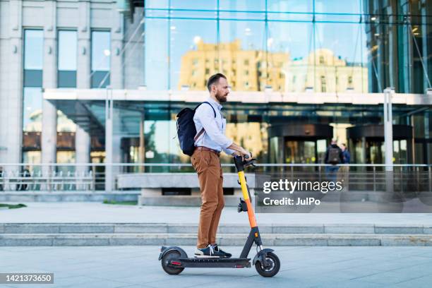young adult man using electro scooter at the city - electro scooter stock pictures, royalty-free photos & images