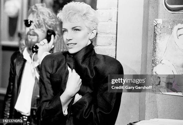 View of English musician Dave Stewart , holding a telephone, and Scottish musician Annie Lennox, both of the group Eurythmicss, during an interview...