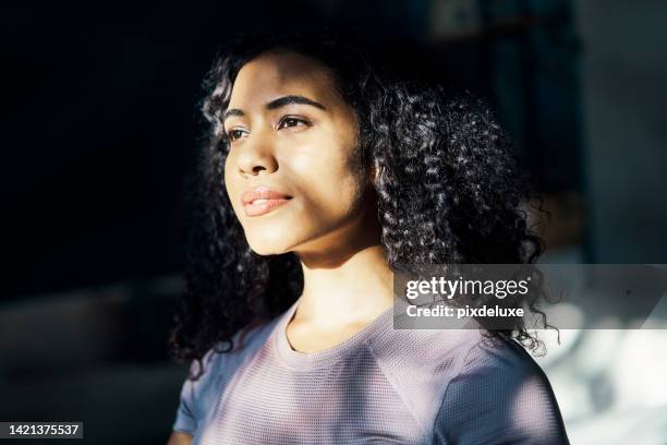 beauty, hope and a woman thinking at a room window, looking outside, with sunshine in her face. happy morning, a smile and dreaming of summer romance, girl lost in romantic thoughts in her bedroom - happy faces stockfoto's en -beelden