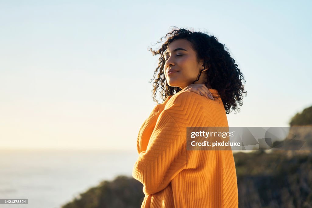 Relax, beach or summer with a woman outdoor and the horizon, sea or ocean in the background during summer. Freedom, self love and nature with a young female on holiday or vacation and hugging herself