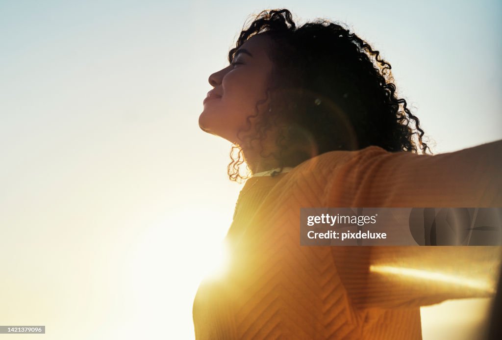 Freedom, flare and sky with a woman outdoor at sunset during summer to relax with fresh air and sunshine. Happy, carefree and mockup with a young female feeling relaxed outside in the morning