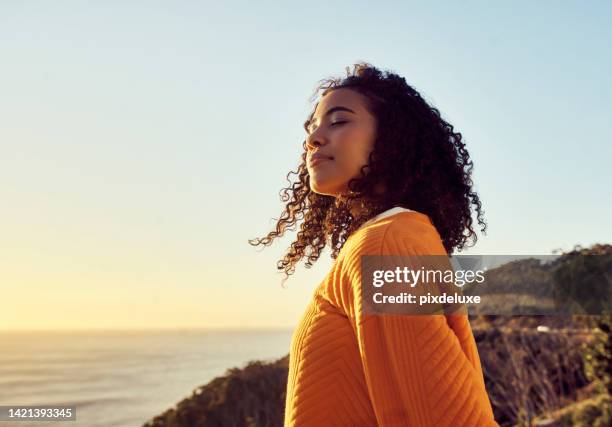 freedom, relax and happy mindset of a woman from brazil with sun on her face at a sea. nature, ocean and beach water sunset with a young person feeling peace, wellness and gratitude from meditation - etéreo imagens e fotografias de stock