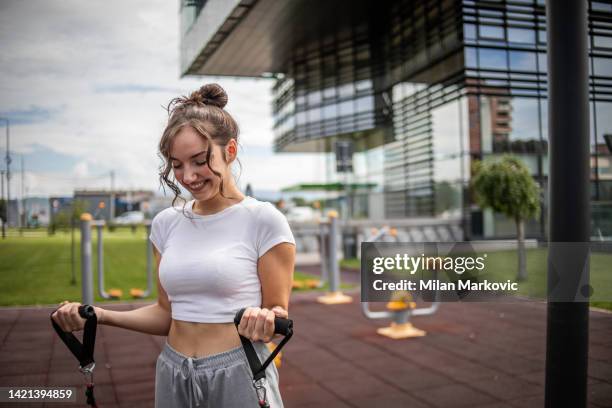 a young female athlete uses a resistance band while exercising outdoors - elastic band ball stock pictures, royalty-free photos & images
