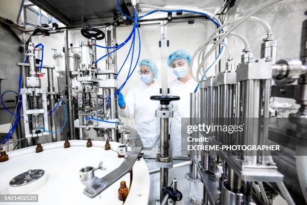 two female employees in a pharmaceutical laboratory seen while controlling the process of drugs manufacturing - pharmaceutical manufacturing machine stock pictures, royalty-free photos & images