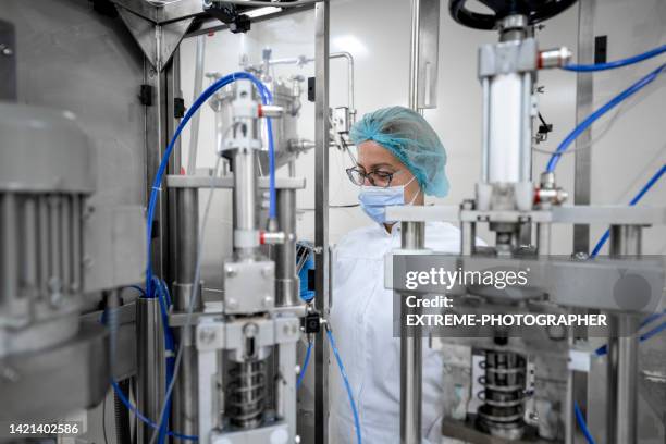 fully equipped technician in protective workwear seen in a pharmaceutical laboratory - pharmaceutical manufacturing machine stock pictures, royalty-free photos & images