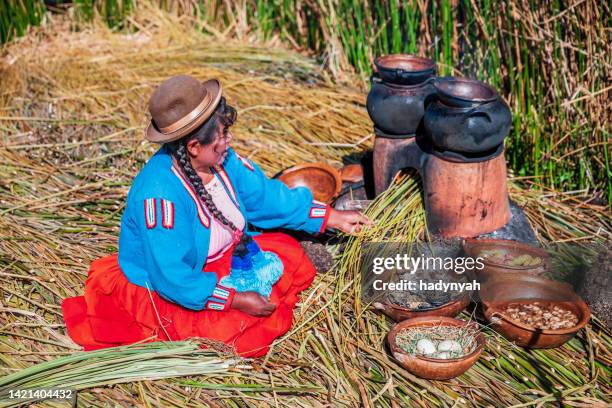 peruvian woman cooking on uros floating island, lake tititcaca - uroseilanden stockfoto's en -beelden