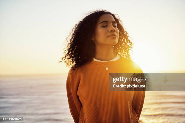 plage, coucher de soleil et femme calme profitant de l’air frais de l’océan tout en se relaxant pendant les vacances de printemps. fille saine, zen et paisible dans une aventure dans la nature avec un style de vie de bien-être, de liberté et de voya - religion photos et images de collection