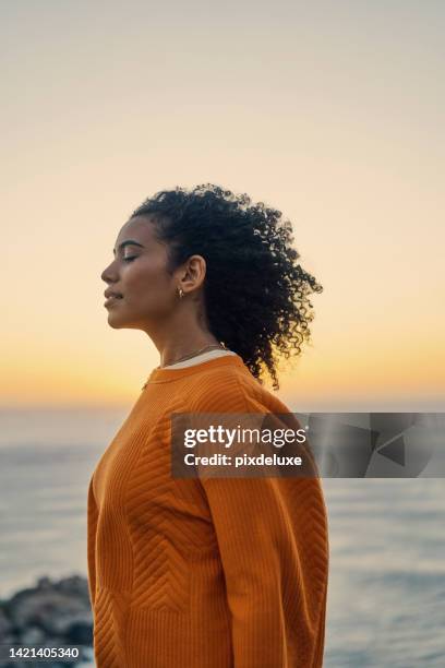 relax, zen and freedom mindset of a woman at the ocean water, beach and sea in nature at sunset. calm and positive energy of a young moroccan female enjoying the sound of content waves at evening - golden hour woman stock pictures, royalty-free photos & images