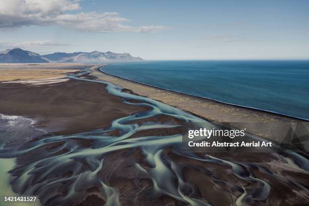 aerial image showing a braided river flowing alongside the coastline, stokksnes, iceland - braided river stock pictures, royalty-free photos & images