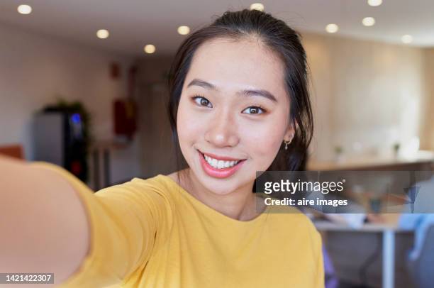 portrait of young asian woman holding camera and smiling with unfocused background - autorretratarse fotografías e imágenes de stock