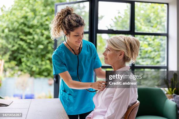 doctor listening to the heartbeat of a woman at home - listening to heartbeat 個照片及圖片檔