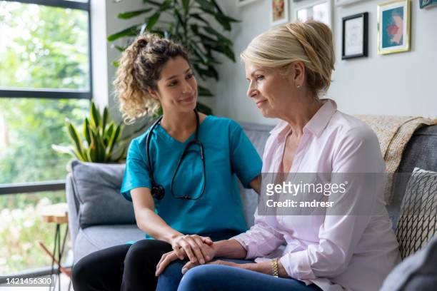 doctor comforting a sick woman while making a house call - nhs england stock pictures, royalty-free photos & images