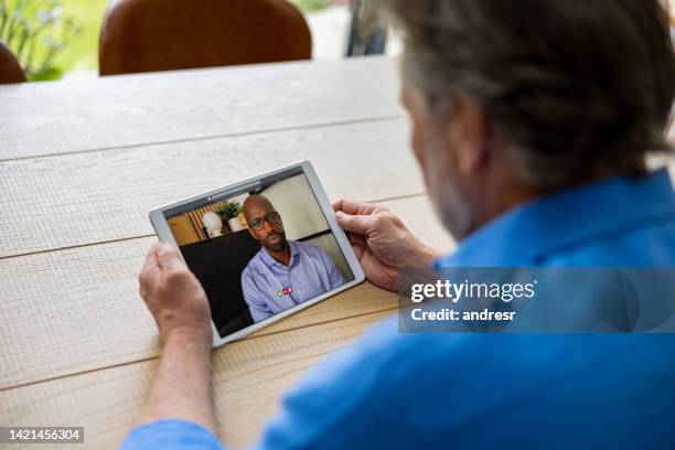 man at home talking to a doctor on a video call - virtual visit stock pictures, royalty-free photos & images