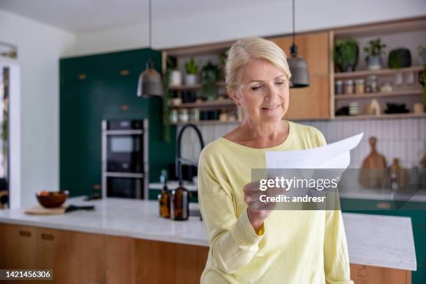 happy woman at home reading a letter she got in the mail - reading letter stock pictures, royalty-free photos & images