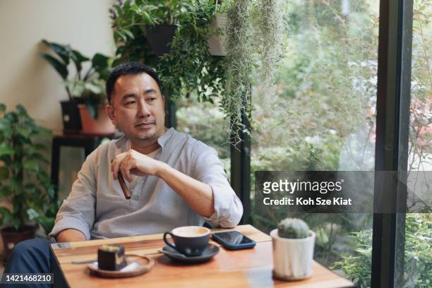 hombre chino asiático retirado relajándose solo en un café interior - cigar fotografías e imágenes de stock