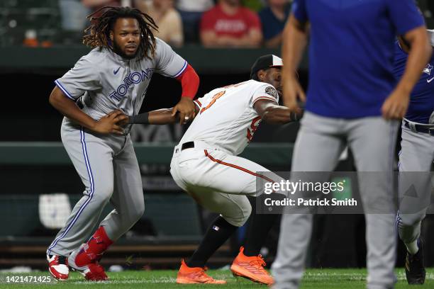 Vladimir Guerrero Jr. #27 of the Toronto Blue Jays is held back by Jorge Mateo of the Baltimore Orioles after the benches cleared during the seventh...