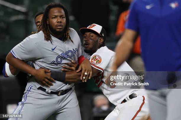 Vladimir Guerrero Jr. #27 of the Toronto Blue Jays is held back by Jorge Mateo of the Baltimore Orioles after the benches cleared during the seventh...