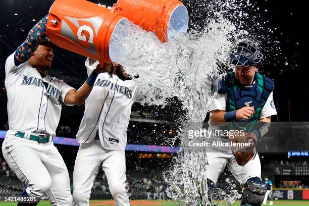 Julio Rodriguez and J.P. Crawford douse Cal Raleigh of the Seattle Mariners after the game against the Chicago White Sox at T-Mobile Park on...