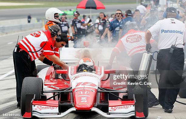 Justin Wilson of England, driver of the Dale Coyne Racing Honda, escapes the car as smoke emits from the engine during practice for the IndyCar...