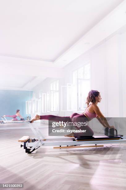 female athlete exercising on a pilates machine in a health club. - reformer stock pictures, royalty-free photos & images