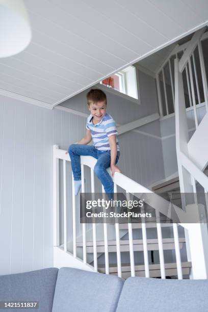boy sliding on the staircase in the house - balustrade stock pictures, royalty-free photos & images