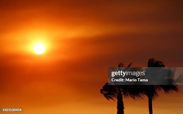 The sun sets through the haze of wildfire smoke as the Fairview Fire burns on September 6, 2022 near Hemet, California. The 4,500 acre brush fire has...