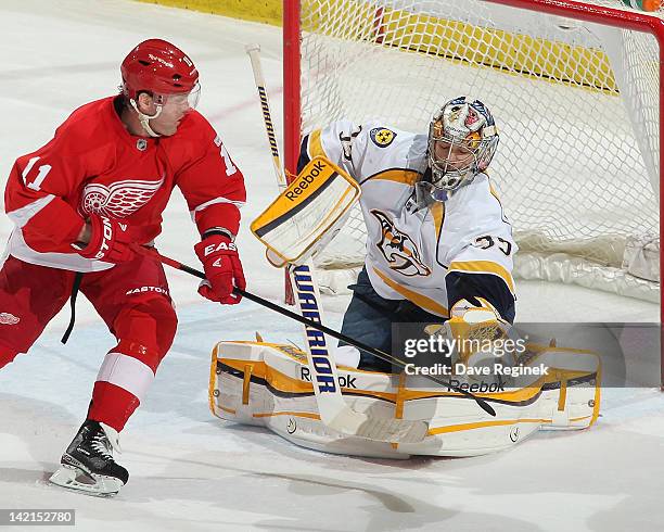 Pekka Rinne of the Nashville Predators makes a glove save as Dan Cleary of the Detroit Red Wings looks for the rebound during an NHL game at Joe...
