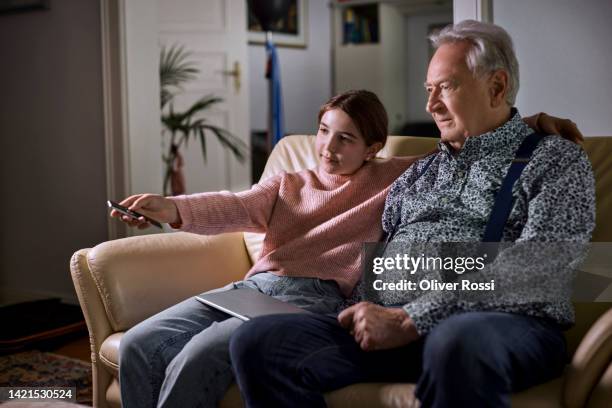 grandfather and granddaughter watching tv together on sofa - granddaughter stock pictures, royalty-free photos & images