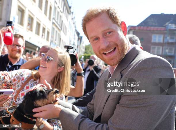 Prince Harry, Duke of Sussex holds a dog as he meets members of the public as they leave the town hall during the Invictus Games Dusseldorf 2023 -...