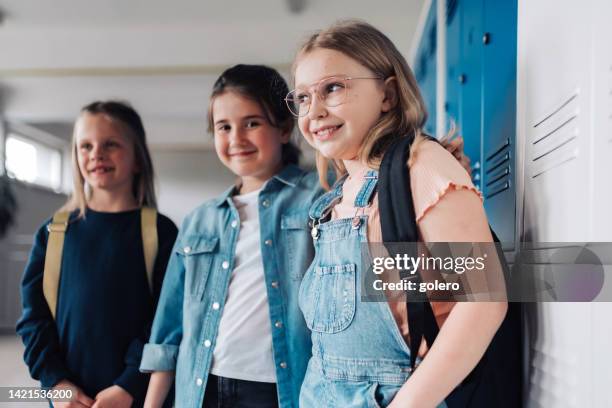 three elementary school girls leaning at locker in school - child report card stock pictures, royalty-free photos & images