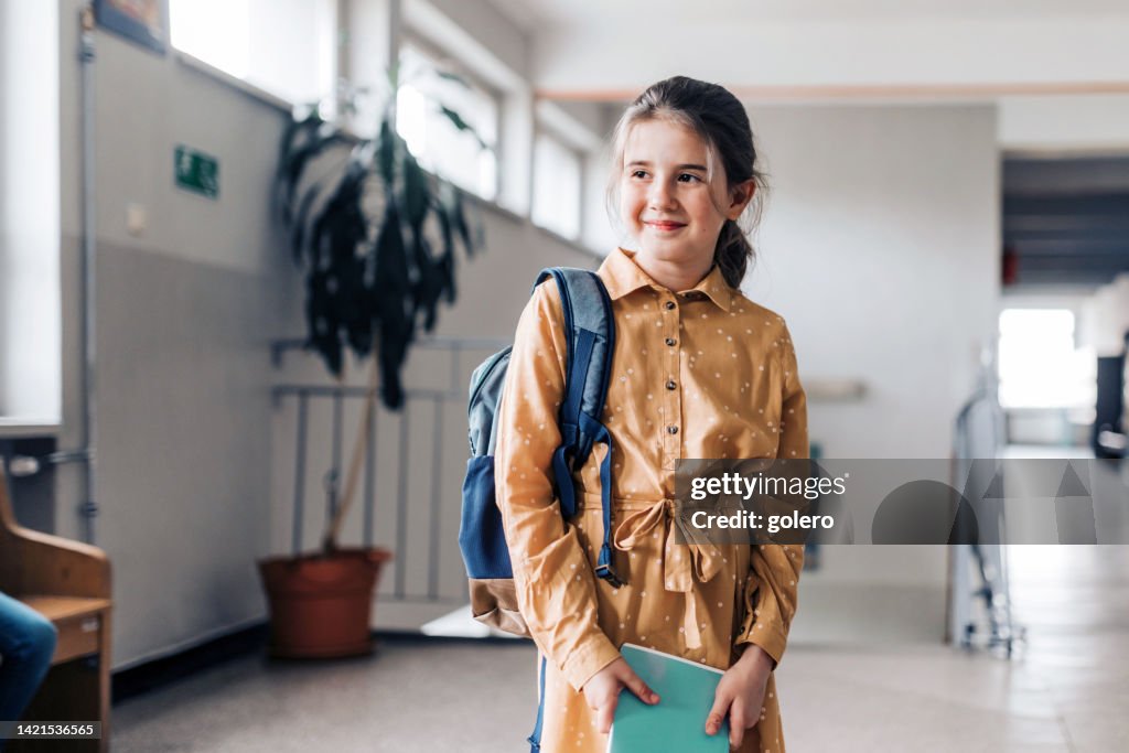 Portraits of happy elementary schoolgirl holding workbook