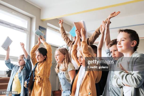 group of elementary school children raising up hands together - kid cheering stock pictures, royalty-free photos & images