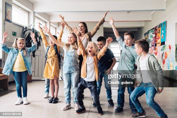 group of elementary school children with teacher raising up hands together - kid cheering stock pictures, royalty-free photos & images