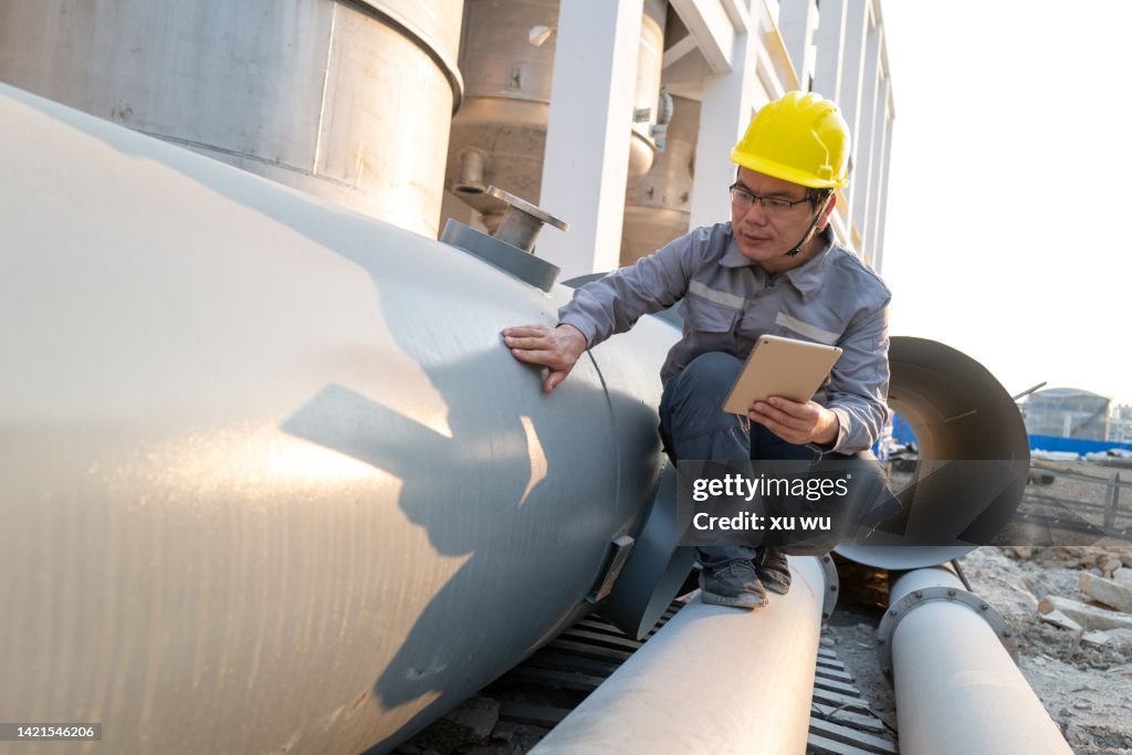 Chemical plant construction site engineer checking equipment quality