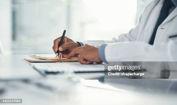 o médico escreve em papel ou documento em uma mesa no hospital. profissional de saúde elaborando uma carta de seguro médico, papelada legal ou formulário. um gp arquivando um documento em um consultório de clínica - registro médico - fotografias e filmes do acervo