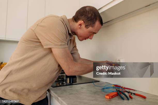 male technician fixing outlet in kitchen at home - schroevendraaier stockfoto's en -beelden