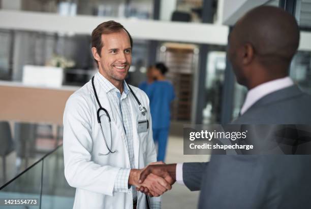 doctor, hospital and handshake with businessman or patient, meeting, consulting or life insurance. health, partnership and smile with medical, healthcare and support in research clinic collaboration - scientist in lab coat stock pictures, royalty-free photos & images