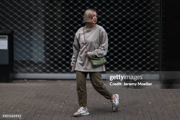 Franzi Koenig wearing Acne Studios oversized beige sweater, New Balance XC 72 sneaker, Fafe Collection jewelry, H&M pants, Saint Laurent bag on...
