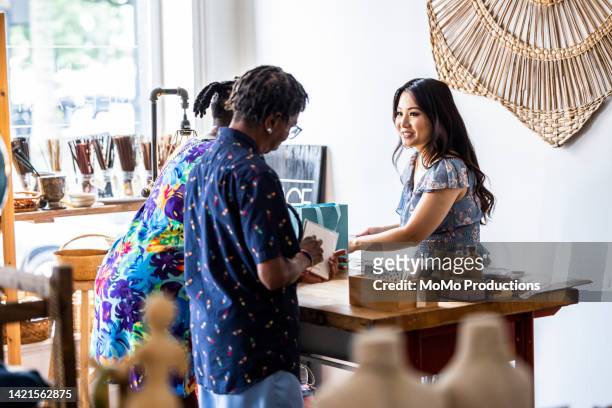 lesbian couple making a purchase at a female owned small business - lgbt mobile foto e immagini stock