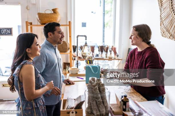 young couple making a purchase at a female owned small business - sales assistant furniture stock pictures, royalty-free photos & images