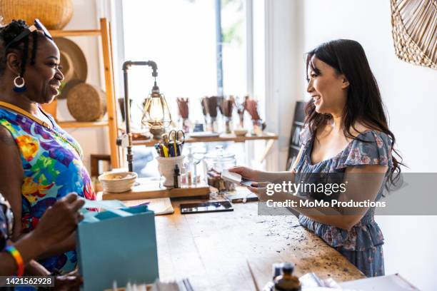 lesbian couple making a purchase at a female owned small business - pride merchandise stock pictures, royalty-free photos & images