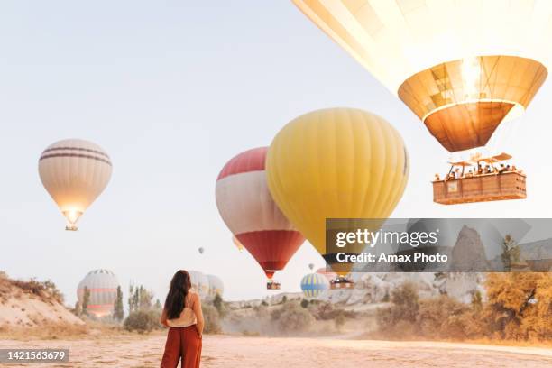young woman feels happy and smiling while looking at hot air balloons in cappadocia - capadócia imagens e fotografias de stock