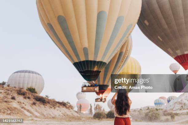 junge touristin, die auf dem smartphone ein foto von heißluftballons in kappadokien macht - ballon festival stock-fotos und bilder