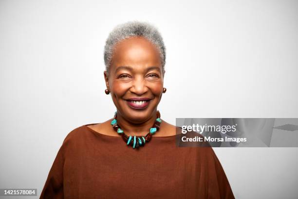 close-up portrait of confident african american businesswoman is against white background. - senior adult white background stock pictures, royalty-free photos & images