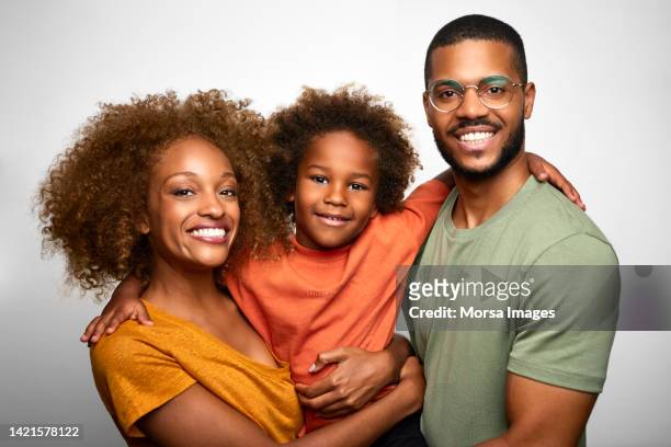 portrait of african american young family with one child against white background. - images of black families stock pictures, royalty-free photos & images