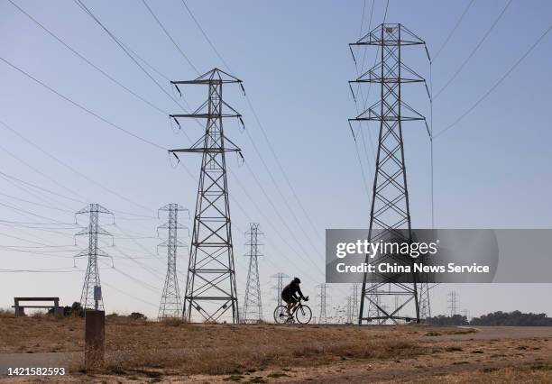 Cyclist rides past electricity pylons at a park during a heatwave on September 5, 2022 in San Mateo County, California.