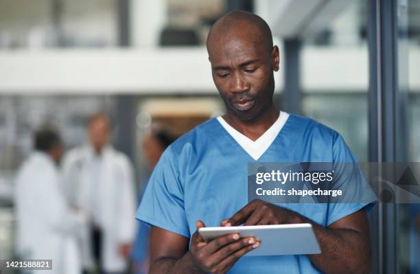 healthcare, internet and a black doctor on a tablet, reading email, patient info or medical journal online. young medical employee or male nurse consulting the web and working in a hospital or clinic - medical writer stock pictures, royalty-free photos & images