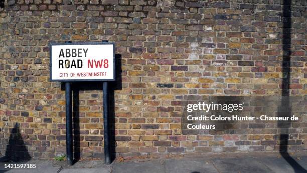 weathered brick wall with street name sign and sidewalk in london, england, uk - abbey road london stock-fotos und bilder